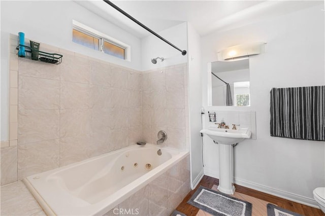 9824 Evelyn Ave, California City, CA 93505 - full bathroom with toilet, a combined bath / shower with jetted tub, wood finished floors, a sink, and baseboards