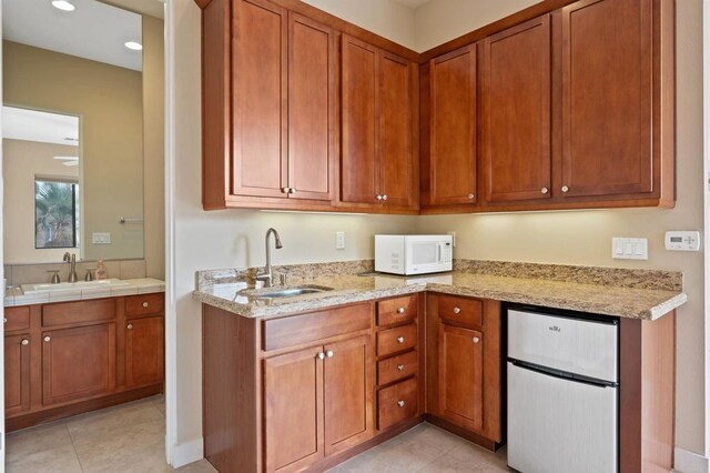 74158 Pele Pl, Palm Desert, CA 92211 - kitchen with stainless steel refrigerator, white microwave, a sink, brown cabinetry, and recessed lighting