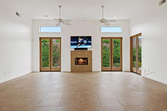 74158 Pele Pl, Palm Desert, CA 92211 - unfurnished living room with ceiling fan, tile patterned floors, a warm lit fireplace, a high ceiling, and recessed lighting