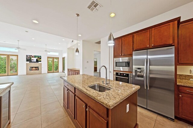 74158 Pele Pl, Palm Desert, CA 92211 - kitchen featuring appliances with stainless steel finishes, a sink, light tile patterned floors, an island with sink, and light stone counters