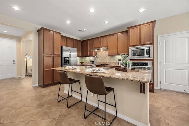 298 W Pebble Creek Ln, Orange, CA 92865 - kitchen featuring appliances with stainless steel finishes, decorative backsplash, light tile patterned flooring, a breakfast bar, and light stone countertops