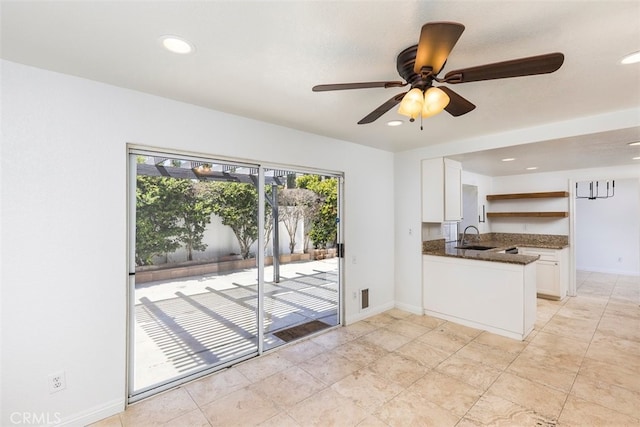 28705 Bridge Water Ln, Menifee, CA 92584 - kitchen with white cabinets, open shelves, ceiling fan, a peninsula, and dark stone counters