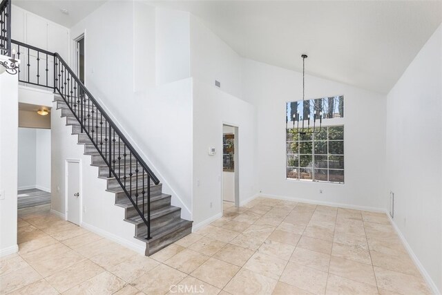 28705 Bridge Water Ln, Menifee, CA 92584 - staircase with high vaulted ceiling, a chandelier, and tile patterned floors
