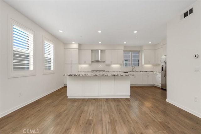 175 Cadence, Irvine, CA 92618 - kitchen with wall chimney exhaust hood, stainless steel fridge, healthy amount of natural light, white cabinetry, and recessed lighting