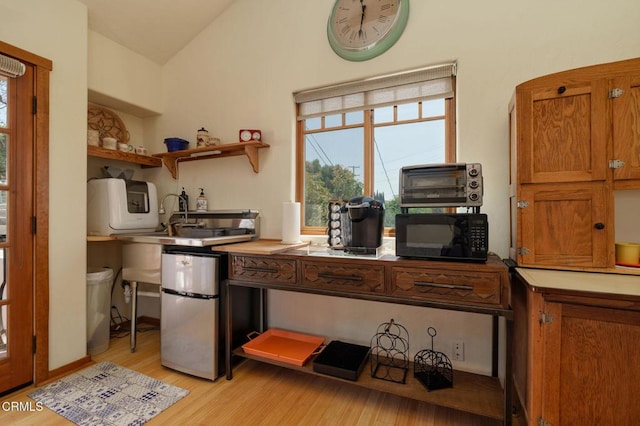 422 Foothill Dr, Fillmore, CA 93015 - kitchen with black microwave, light wood finished floors, brown cabinets, freestanding refrigerator, and lofted ceiling