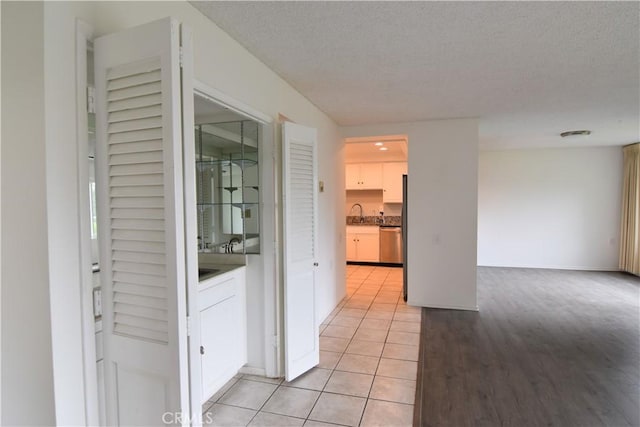5369 Algarrobo Unit 1G, Laguna Woods, CA 92637 - hallway with a textured ceiling, light tile patterned floors, a sink, and baseboards