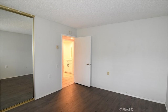 5369 Algarrobo Unit 1G, Laguna Woods, CA 92637 - unfurnished bedroom featuring dark wood-type flooring, a textured ceiling, and a closet