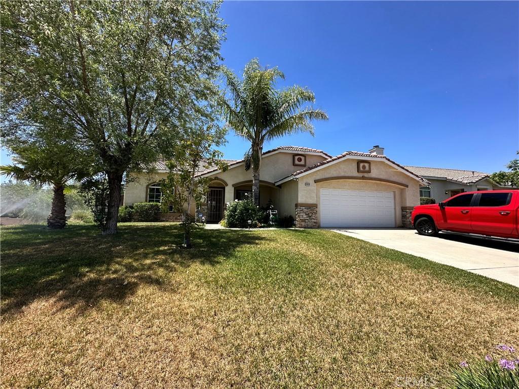 889 Sycamore Ct, Banning, CA 92220 - mediterranean / spanish-style home with stucco siding, a garage, a front yard, driveway, and a chimney