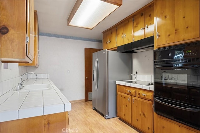 1254 Fieldgate Ave, Hacienda Heights, CA 91745 - kitchen featuring black oven, a warming drawer, tile counters, brown cabinetry, and decorative backsplash