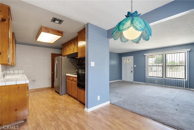 1254 Fieldgate Ave, Hacienda Heights, CA 91745 - kitchen with tile countertops, brown cabinets, a warming drawer, light wood-style floors, and a textured ceiling