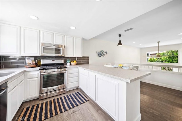 24833 Nueva Vista Dr Unit 2, Laguna Niguel, CA 92677 - kitchen featuring stainless steel appliances, wood finished floors, decorative backsplash, a peninsula, and recessed lighting