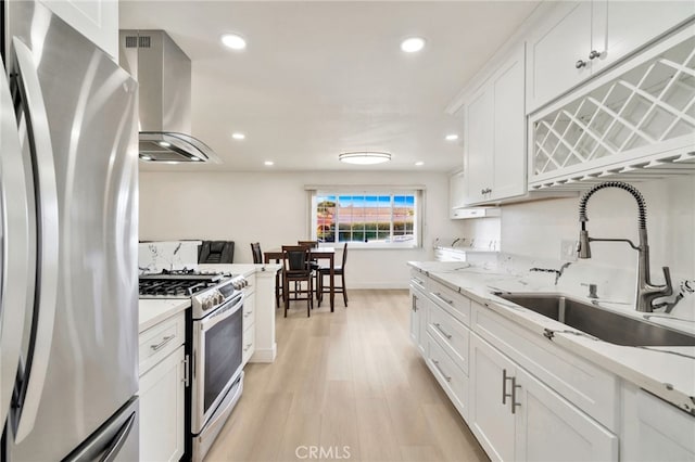 17121 Granada Ln, Huntington Beach, CA 92647 - kitchen featuring freestanding refrigerator, range with gas stovetop, a sink, wall chimney exhaust hood, and light wood-type flooring
