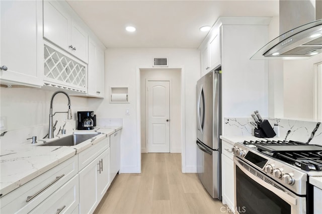 17121 Granada Ln, Huntington Beach, CA 92647 - kitchen featuring stainless steel appliances, wall chimney range hood, a sink, light wood-style floors, and white cabinetry