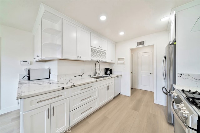 17121 Granada Ln, Huntington Beach, CA 92647 - kitchen with a sink, appliances with stainless steel finishes, white cabinetry, light wood finished floors, and recessed lighting