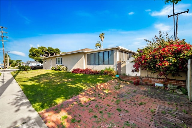 17121 Granada Ln, Huntington Beach, CA 92647 - view of front of house featuring a front lawn, a patio, stucco siding, and a sunroom