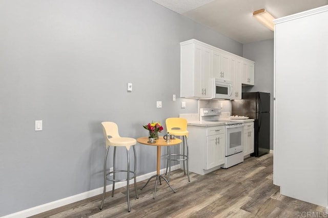 8328 Regents Rd Unit 1K, San Diego, CA 92122 - kitchen featuring white appliances, white cabinetry, wood finished floors, a breakfast bar area, and light countertops