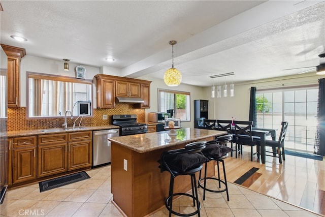 302 E 213th St, Carson, CA 90745 - kitchen featuring appliances with stainless steel finishes, a sink, under cabinet range hood, brown cabinetry, and light tile patterned flooring