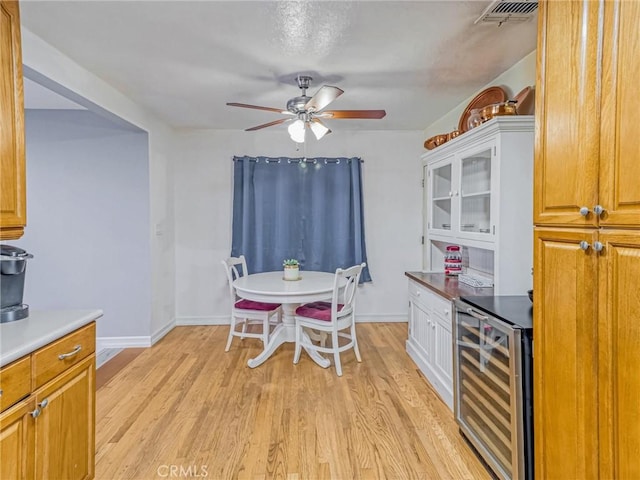 5436 Bonfair Ave, Lakewood, CA 90712 - dining space with beverage cooler, a ceiling fan, light wood-style flooring, baseboards, and a bar
