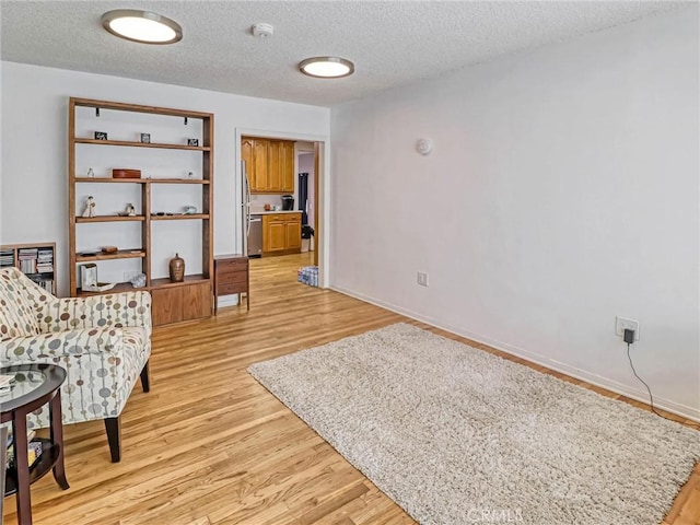 5436 Bonfair Ave, Lakewood, CA 90712 - living area featuring a textured ceiling, light wood-style floors, and baseboards