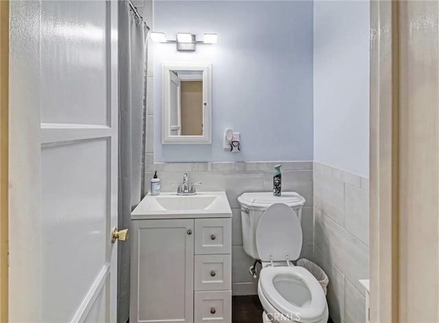 5436 Bonfair Ave, Lakewood, CA 90712 - bathroom featuring toilet, vanity, tile walls, a wainscoted wall, and curtained shower