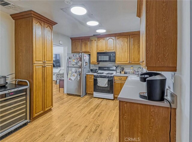 5436 Bonfair Ave, Lakewood, CA 90712 - kitchen featuring freestanding refrigerator, gas stove, black microwave, beverage cooler, and light wood-type flooring