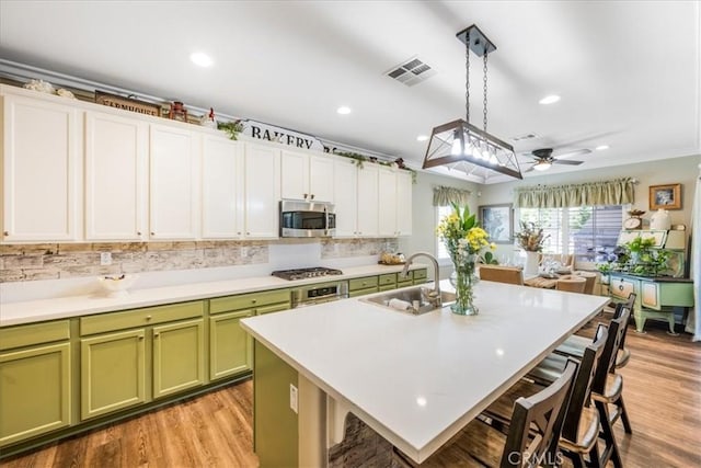25687 Red Hawk Rd, Corona, CA 92883 - kitchen featuring appliances with stainless steel finishes, green cabinetry, a breakfast bar area, a ceiling fan, and light countertops