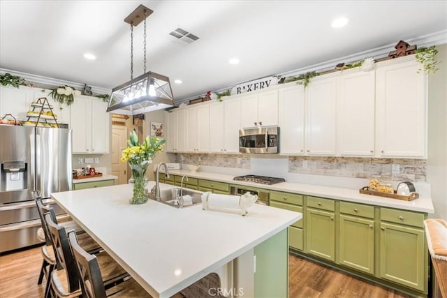 25687 Red Hawk Rd, Corona, CA 92883 - kitchen with green cabinets, appliances with stainless steel finishes, a breakfast bar, light countertops, and recessed lighting