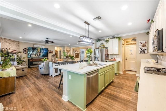 25687 Red Hawk Rd, Corona, CA 92883 - kitchen featuring green cabinets, appliances with stainless steel finishes, open floor plan, a center island with sink, and ornamental molding