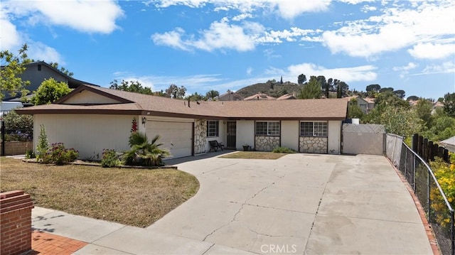 26111 Abdale St, Newhall, CA 91321 - view of front of house with stone siding, an attached garage, driveway, and stucco siding