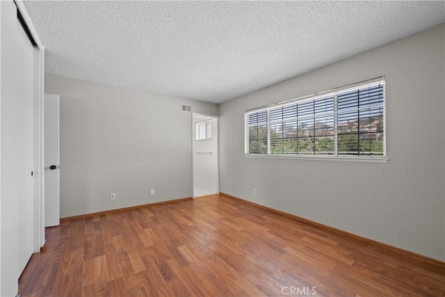 26111 Abdale St, Newhall, CA 91321 - empty room with wood finished floors, a textured ceiling, and baseboards