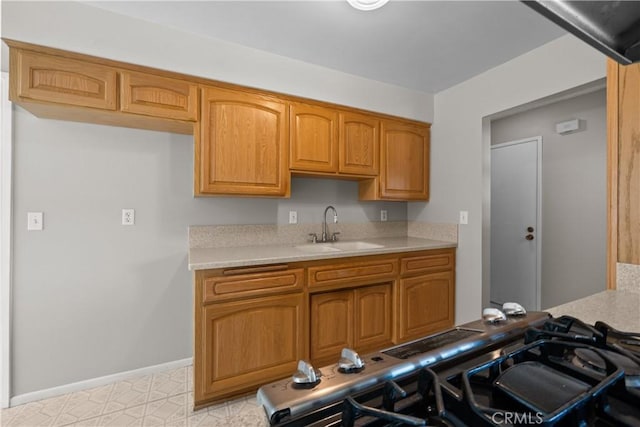26111 Abdale St, Newhall, CA 91321 - kitchen featuring a sink, light countertops, baseboards, and brown cabinetry
