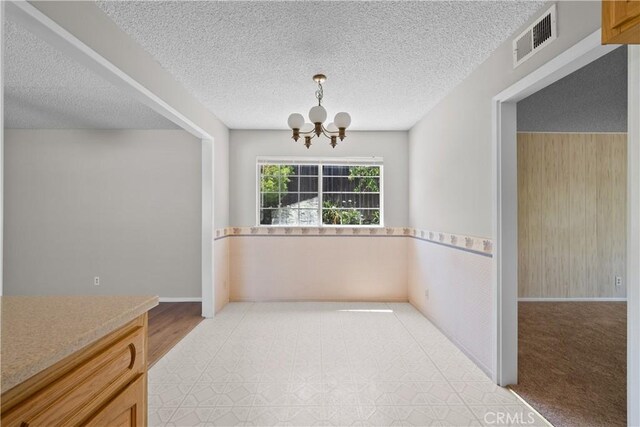 26111 Abdale St, Newhall, CA 91321 - unfurnished dining area featuring a chandelier, baseboards, and a textured ceiling