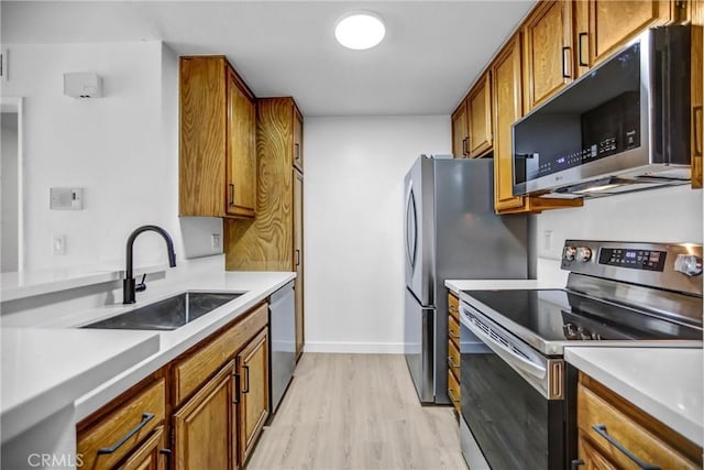 4499 Via Marisol Unit 105A, Los Angeles, CA 90042 - kitchen with appliances with stainless steel finishes, a sink, brown cabinetry, light wood-style flooring, and light countertops