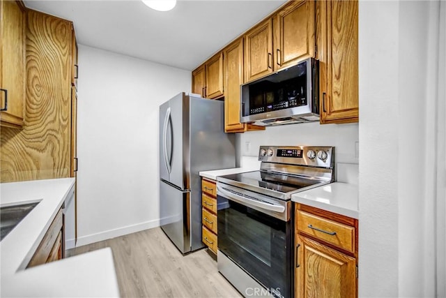 4499 Via Marisol Unit 105A, Los Angeles, CA 90042 - kitchen featuring stainless steel appliances, light wood-style flooring, brown cabinets, light countertops, and baseboards