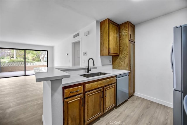 4499 Via Marisol Unit 105A, Los Angeles, CA 90042 - kitchen with a sink, appliances with stainless steel finishes, light wood-style flooring, light countertops, and a peninsula