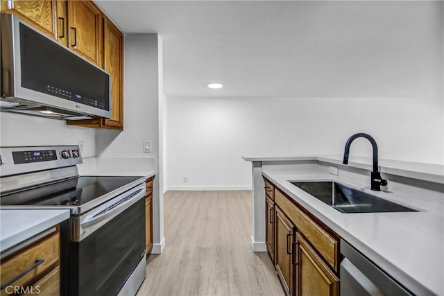 4499 Via Marisol Unit 105A, Los Angeles, CA 90042 - kitchen with appliances with stainless steel finishes, a sink, brown cabinets, light wood finished floors, and light countertops