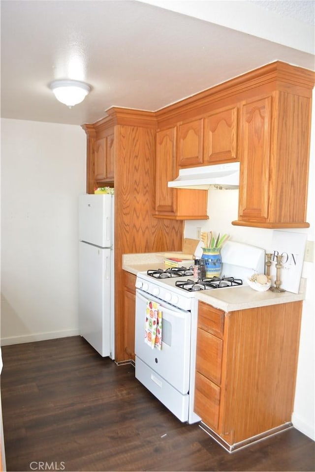 15351 Orange Ave Unit 25, Paramount, CA 90723 - kitchen with white appliances, under cabinet range hood, light countertops, dark wood-style floors, and baseboards