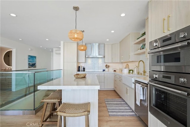 11938 Whitewater Ln, Malibu, CA 90265 - kitchen with wall chimney exhaust hood, appliances with stainless steel finishes, modern cabinets, a kitchen island, and light countertops