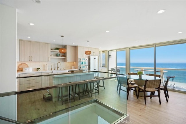 11938 Whitewater Ln, Malibu, CA 90265 - kitchen with stainless steel appliances, light brown cabinets, light wood-style flooring, decorative backsplash, and a wall of windows