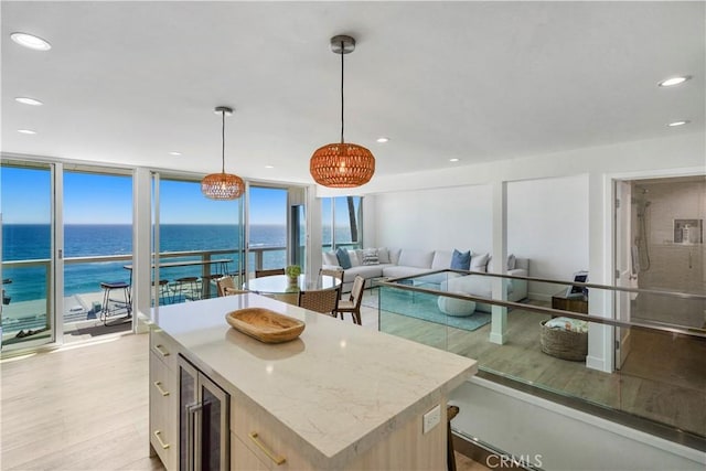 11938 Whitewater Ln, Malibu, CA 90265 - kitchen with wine cooler, light wood-type flooring, a water view, a kitchen island, and decorative light fixtures