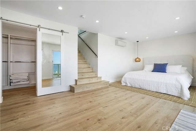 11938 Whitewater Ln, Malibu, CA 90265 - bedroom featuring a wall mounted AC, wood finished floors, recessed lighting, a barn door, and baseboards