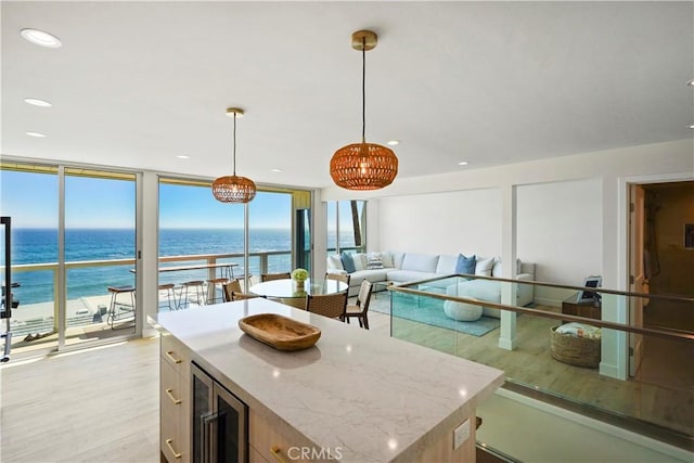 11938 Whitewater Ln, Malibu, CA 90265 - kitchen featuring beverage cooler, light wood-style flooring, expansive windows, a water view, and light stone countertops