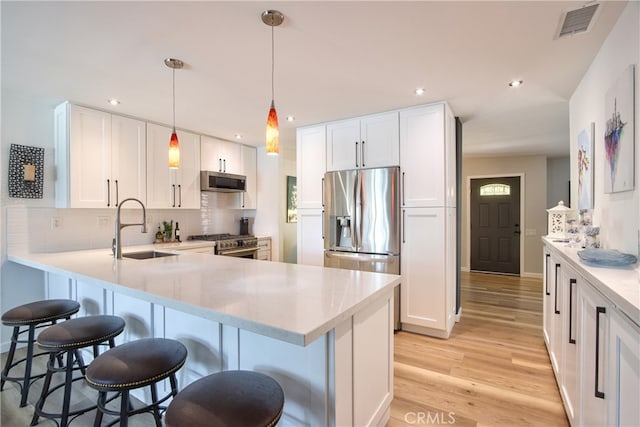 27071 Crews Hill Dr, Menifee, CA 92586 - kitchen with appliances with stainless steel finishes, a sink, light wood-style floors, a kitchen bar, and a peninsula