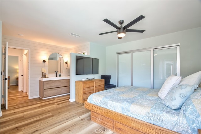 27071 Crews Hill Dr, Menifee, CA 92586 - bedroom with light wood-style floors, a closet, ceiling fan, connected bathroom, and wood walls