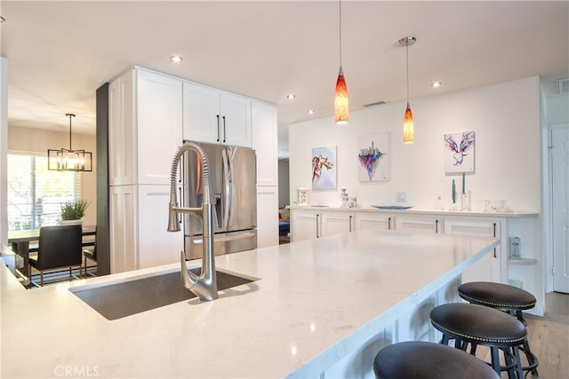 27071 Crews Hill Dr, Menifee, CA 92586 - kitchen featuring stainless steel fridge with ice dispenser, a sink, a breakfast bar area, white cabinets, and pendant lighting