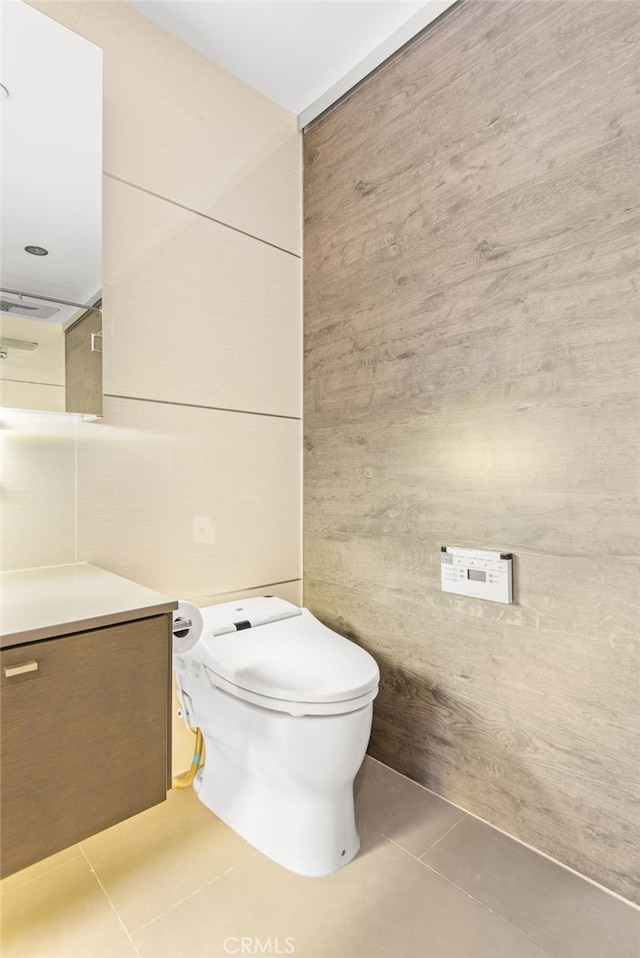 121 S Hope St Unit 9, Los Angeles, CA 90012 - bathroom with tile patterned floors, vanity, wood walls, and toilet