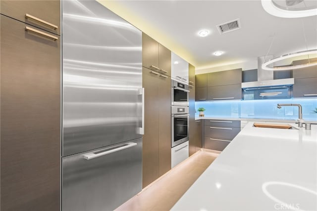 121 S Hope St Unit 9, Los Angeles, CA 90012 - kitchen with modern cabinets, a sink, appliances with stainless steel finishes, wall chimney exhaust hood, and light countertops