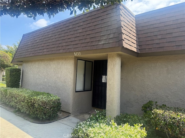 8133 Cardiff Dr, Stanton, CA 90680 - property entrance featuring stucco siding, mansard roof, and roof with shingles