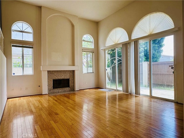 700 Meyer Ln, Redondo Beach, CA 90277 - unfurnished living room featuring healthy amount of natural light, hardwood / wood-style floors, a high end fireplace, and a towering ceiling
