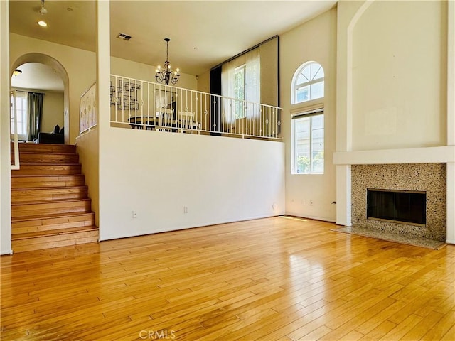 700 Meyer Ln, Redondo Beach, CA 90277 - unfurnished living room with arched walkways, stairway, a chandelier, wood-type flooring, and a high ceiling